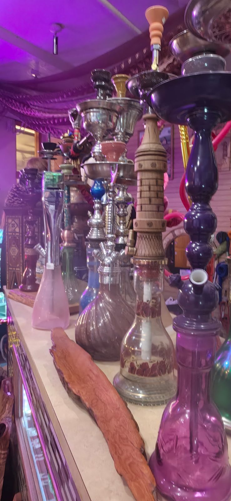 A row of colorful hookahs on display under purple light