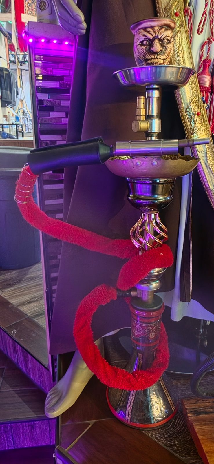 Hookah with a red wrapped hose and a carved face bowl